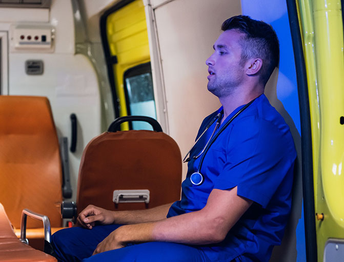 A paramedic sits exhausted in the back of an ambulance.