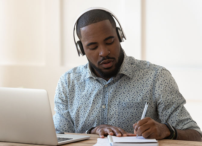 A man with headphones studies at a laptop.