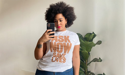 A woman wearing our Ask Now Save LIves campaign T-shirt takes a selfie in the mirror.