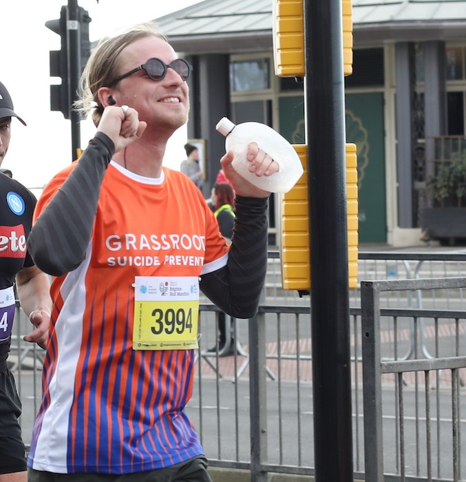 A triumphant young man in a Grassroots Suicide Prevention completes a half marathon