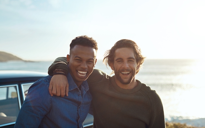 Two happy young men pose on the beach in early evening