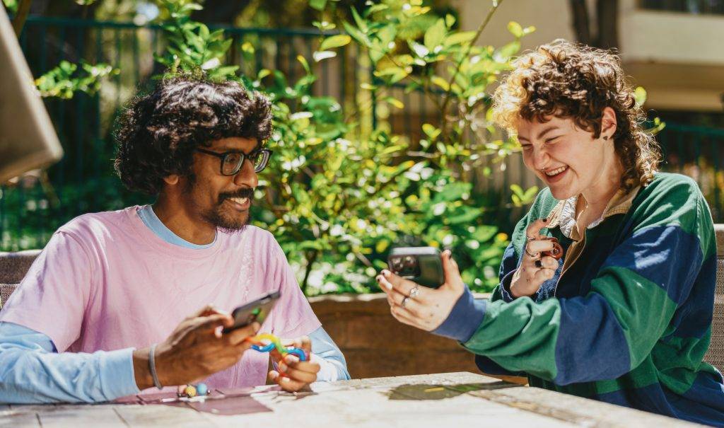 Two friends having a conversation, sharing apps on their phone