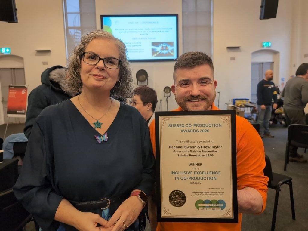 Man and woman smiling and holding an award certificate.