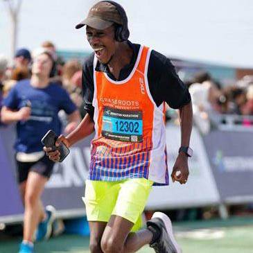 A runner in an orange Grassroots Suicide Prevention best grins as they complete the race.