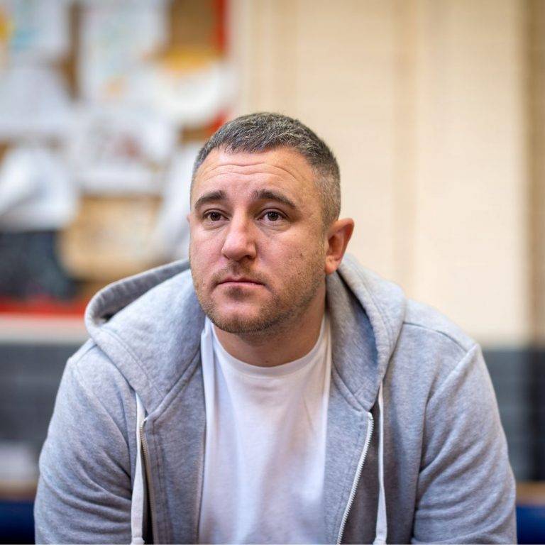 Man in grey hoodie looks off into the distance.