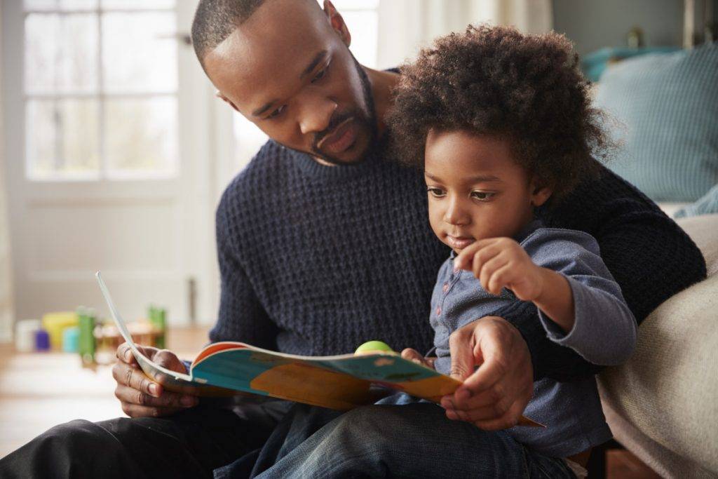 Father And Young Son Reading Book Together At Home stock photo