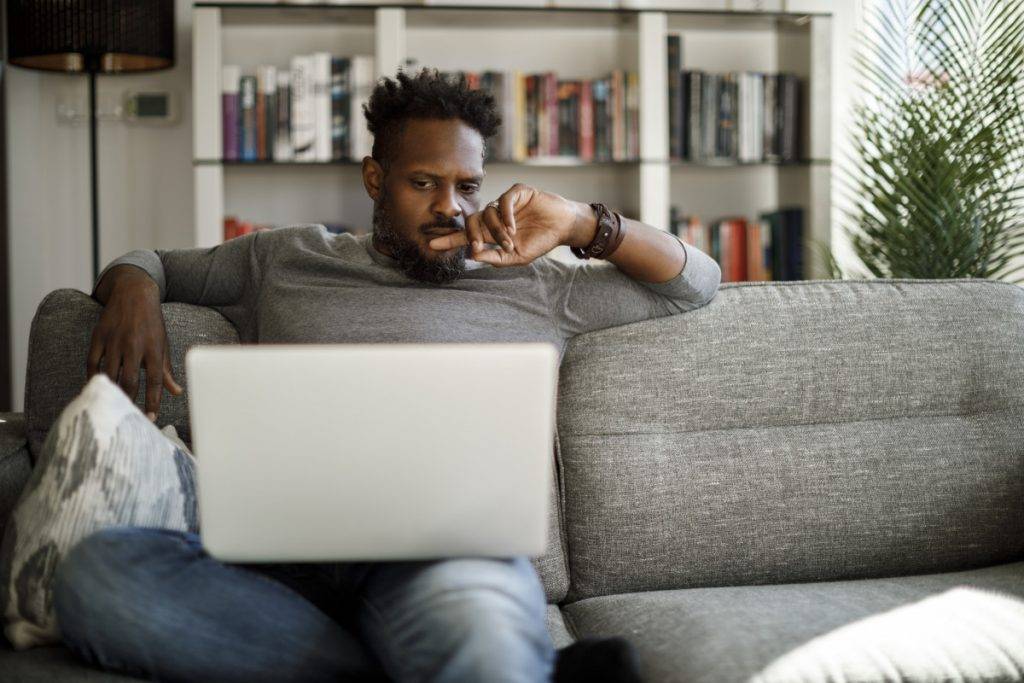 Young man watching movie on laptop at home stock photo