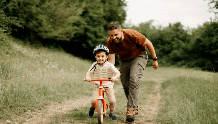 Father teaches son to ride a bike stock photo